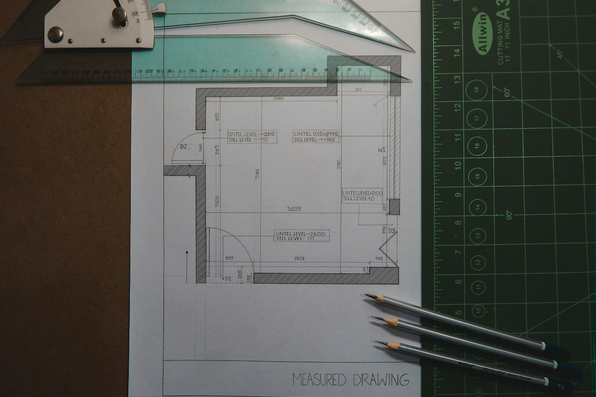 Symbolfoto eines Architekturplans mit Zeichenwerkzeugen; kein ONE7-Grundriss