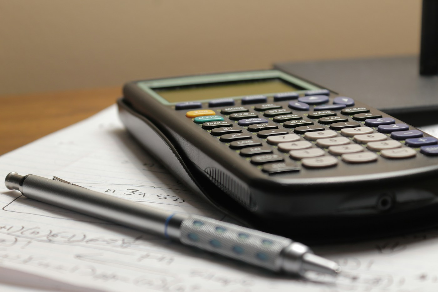 Calculator and pen on a financial worksheet; illustrative rental-management planning photograph